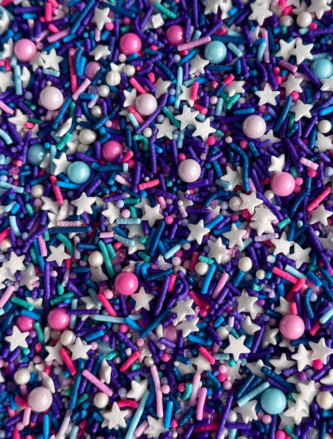 Colorful sprinkles with stars, hearts, and other shapes on a purple background