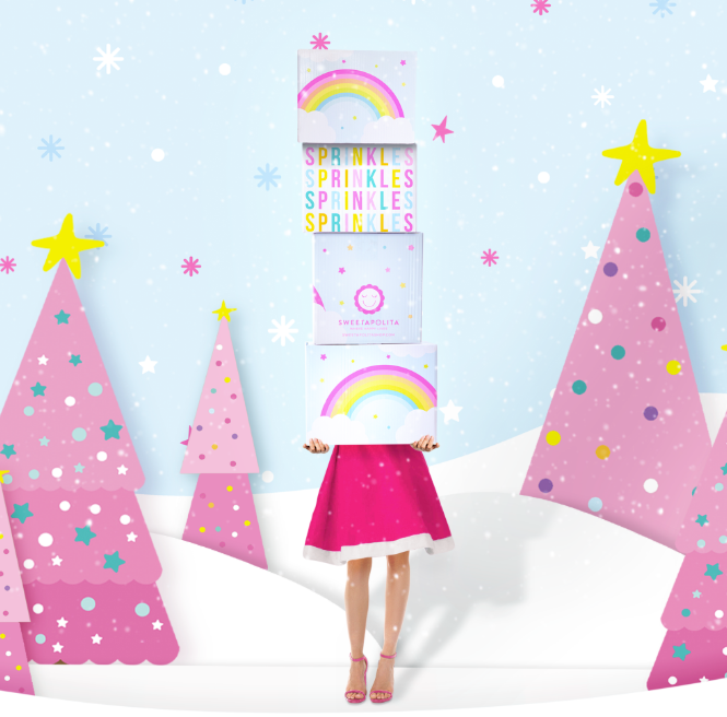 Person holding a rainbow product box with colorful text in a snowy landscape with pink trees.